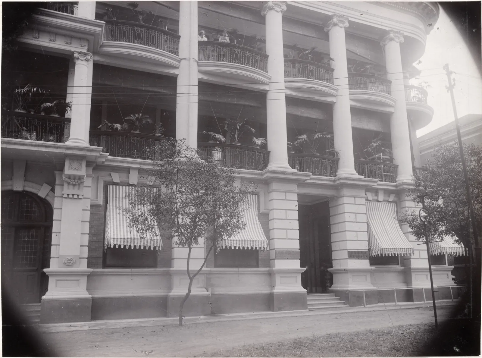 The columns and verandahs of the bank, with striped awnings over the ground-floor windows.